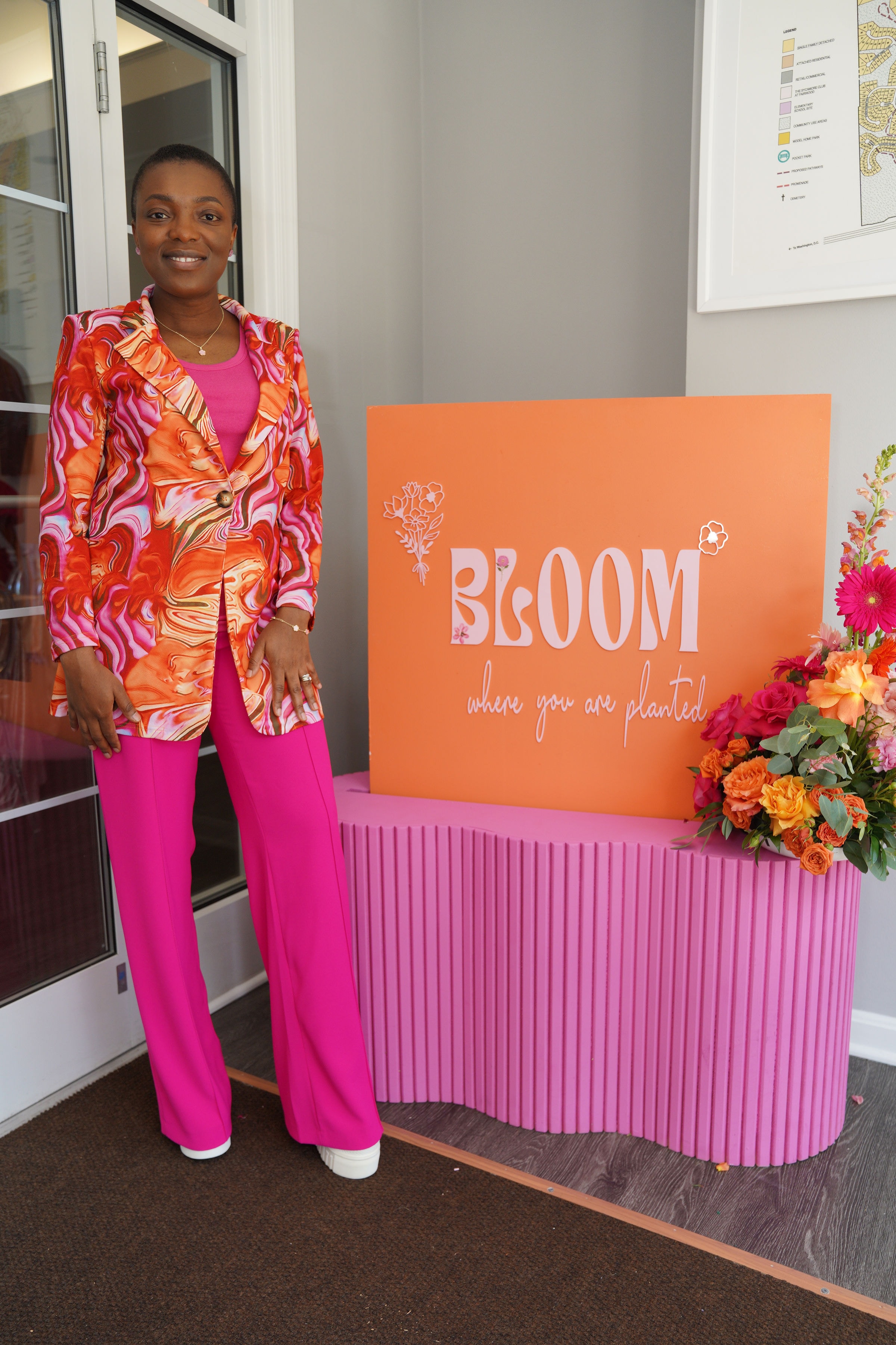 Dr. Angel Mbome at the Bloom event beside the branded signage