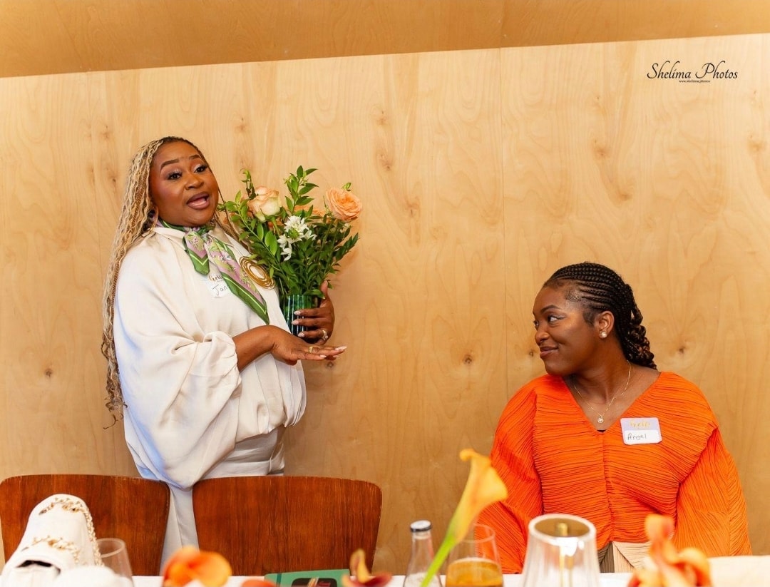 Dr. Angel Mbome holding her book Fragments Don't Scare God while speaking at the Meaningful Experiences event