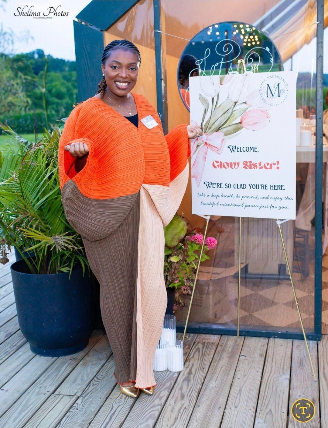 Dr. Angel Mbome posing beside the Meaningful Experiences 'Welcome Glow Sister' event sign at Westminster Winery